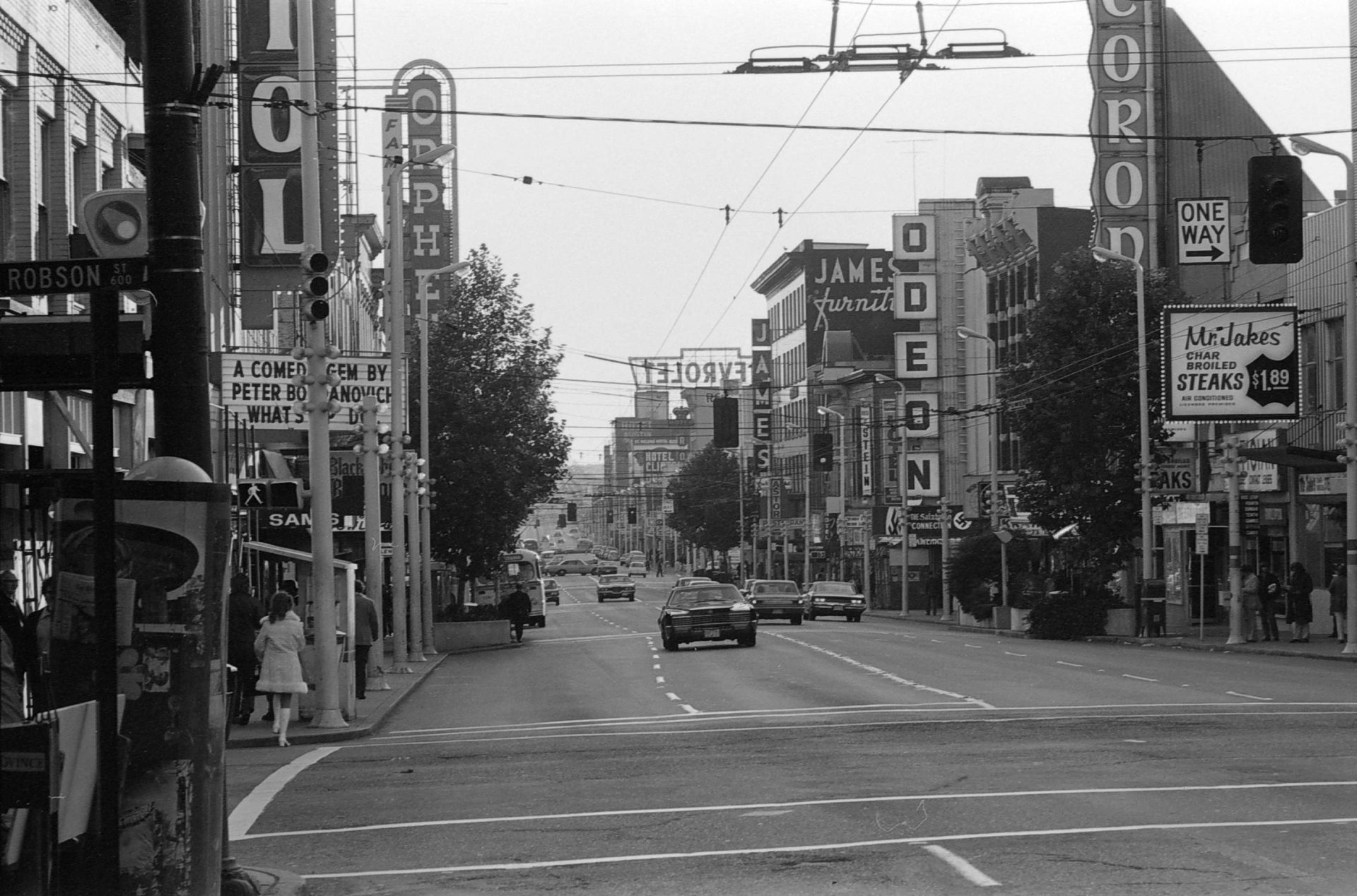 Historic black-and-white photo of Vancouver's Granville Street entertainment district, showing neon theatre signs, marquees, and storefronts near Robson Street.