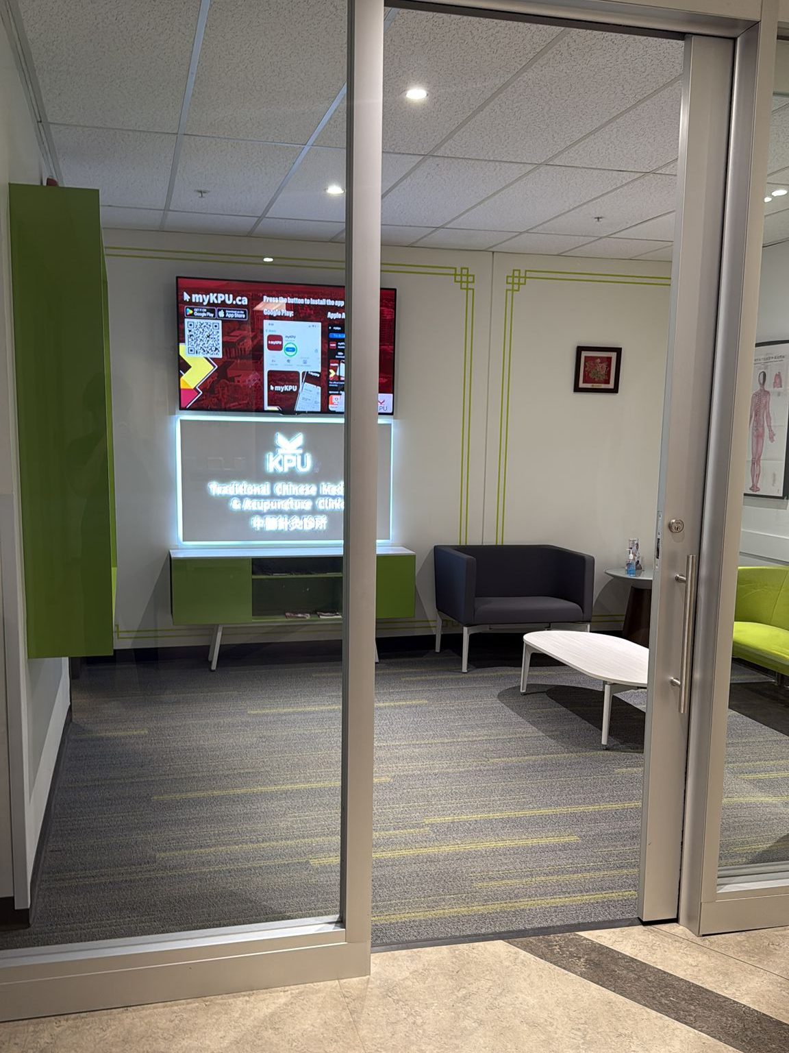 Waiting room with illuminated KPU Traditional Chinese Medicine Clinic signage and seating area.